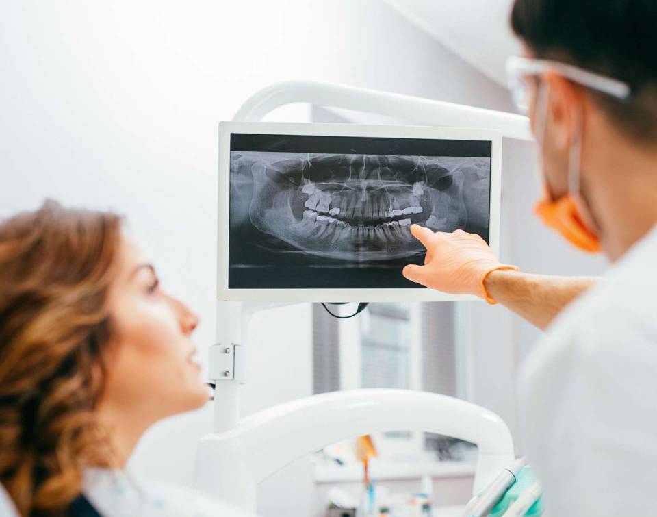 a picture of a patient and dentist looking at an x ray of a mouth